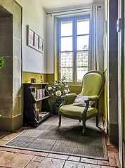 Coin lecture avec fauteuil vert et fenêtre sur le jardin