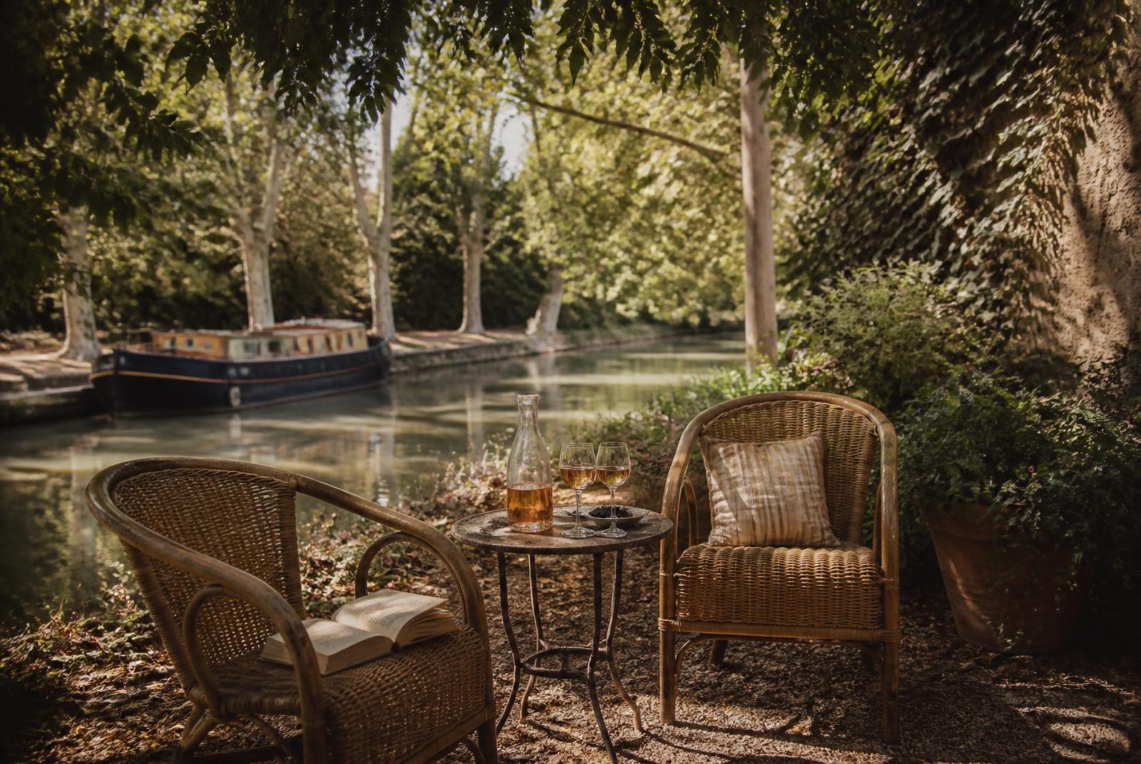 Fauteuils en rotin au bord du Canal du Midi, péniche amarrée