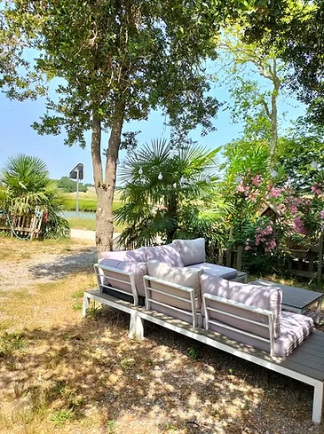 Salon extérieur au bord de l'eau, sous les arbres